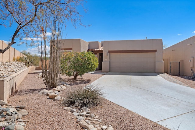 southwest-style home featuring fence, a tiled roof, stucco siding, a garage, and driveway