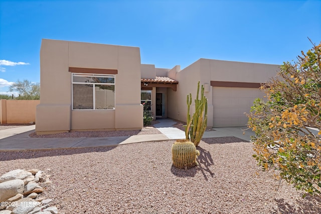 adobe home featuring a tiled roof, a garage, and stucco siding