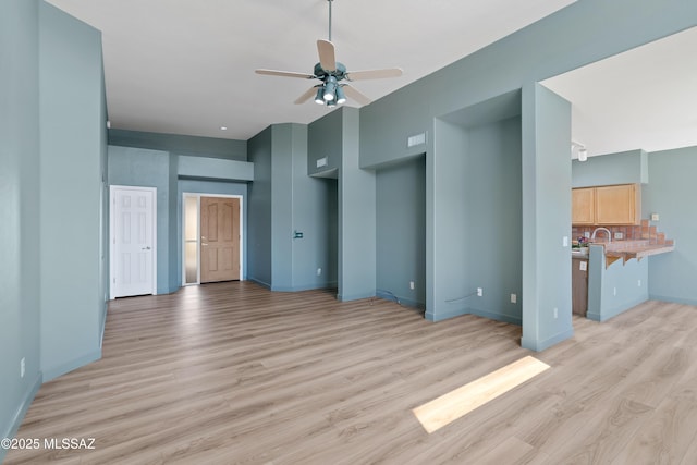 unfurnished living room featuring a ceiling fan, light wood-type flooring, and baseboards