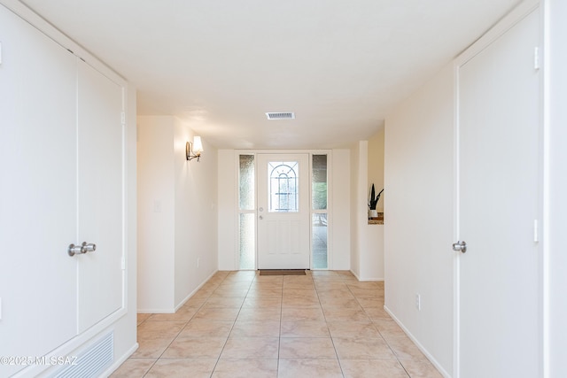 foyer featuring light tile patterned floors, baseboards, and visible vents