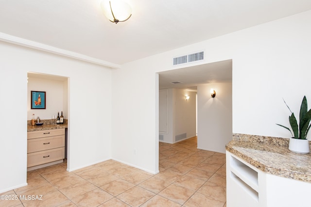 dining room with light tile patterned floors, visible vents, and wet bar