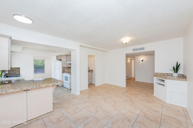 kitchen featuring visible vents, a sink, white appliances, light tile patterned floors, and decorative backsplash