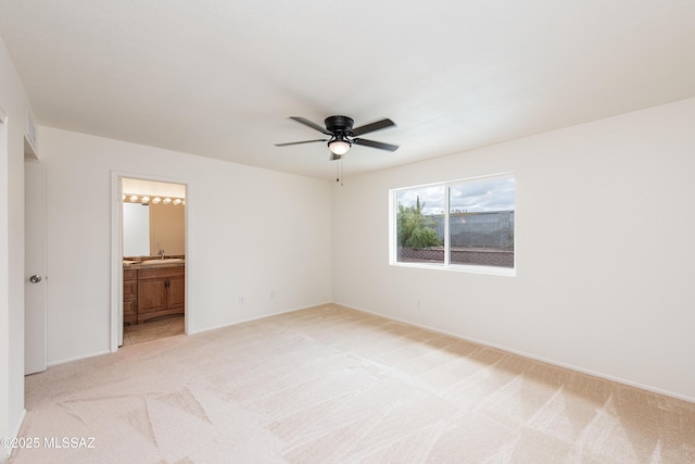 unfurnished bedroom featuring light colored carpet, ceiling fan, and ensuite bathroom