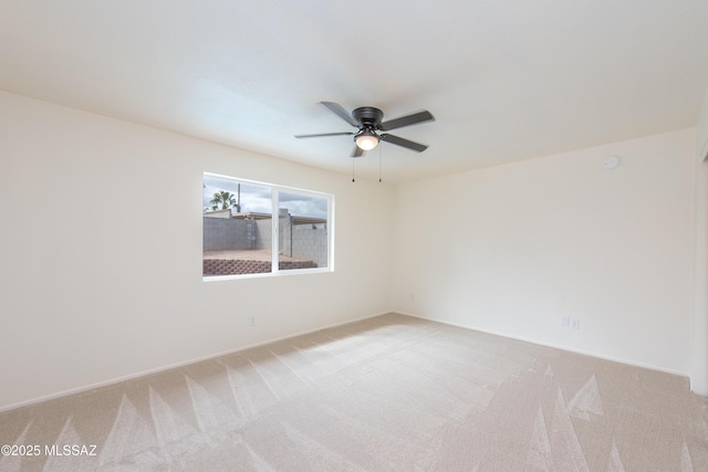 empty room featuring light colored carpet, baseboards, and ceiling fan