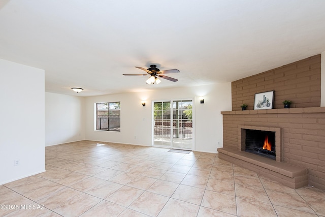 unfurnished living room with light tile patterned floors, a brick fireplace, and ceiling fan