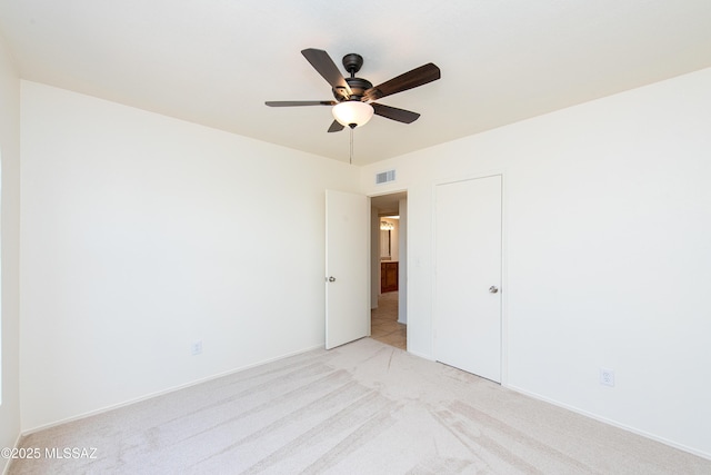 unfurnished bedroom with visible vents, light colored carpet, baseboards, and ceiling fan