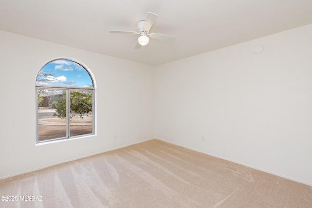 empty room featuring baseboards, light carpet, and ceiling fan