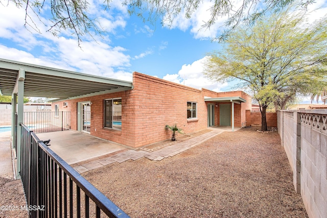 rear view of house with a patio, a fenced backyard, and brick siding