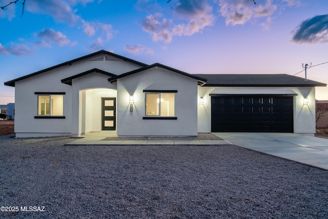 ranch-style house featuring roof with shingles, an attached garage, driveway, and stucco siding