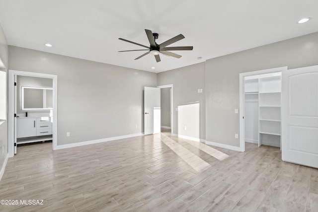 unfurnished bedroom featuring a walk in closet, baseboards, and light wood finished floors