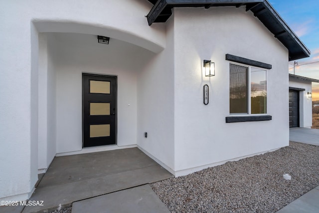 doorway to property with stucco siding and an attached garage