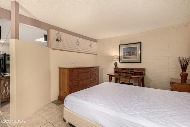 bedroom with a textured ceiling, brick wall, and light tile patterned floors