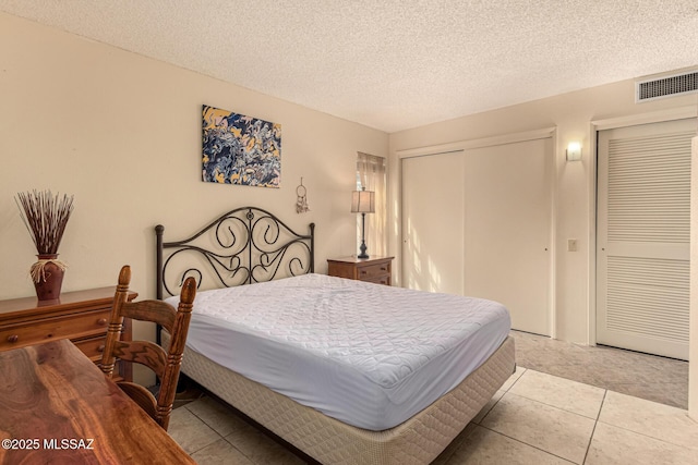 bedroom with visible vents, a textured ceiling, and light tile patterned flooring