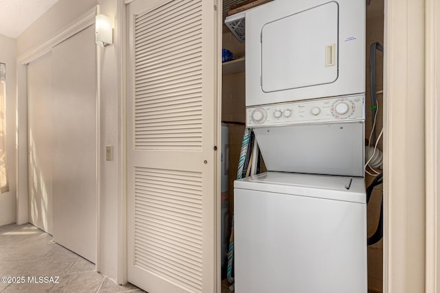 laundry room with laundry area, light tile patterned floors, and stacked washer / drying machine