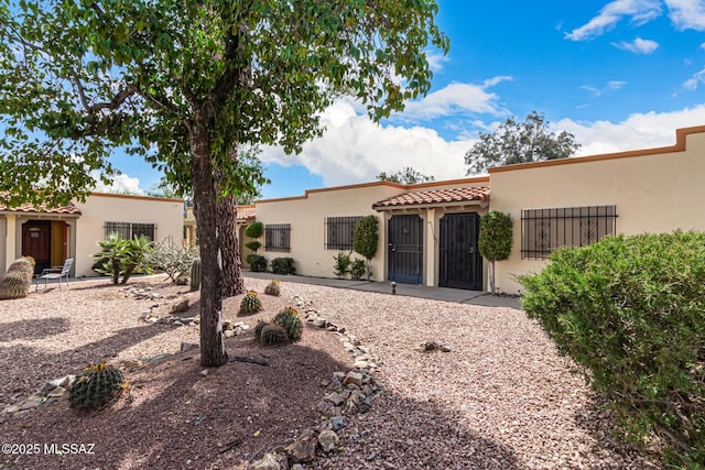 view of front of property with a gate, a tile roof, fence, and stucco siding