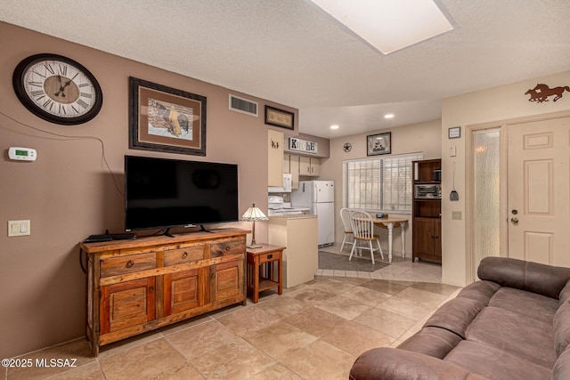 living room with recessed lighting, visible vents, and a textured ceiling