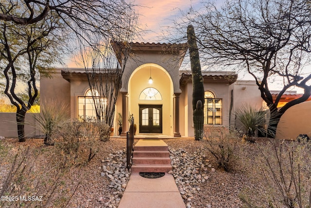 view of front of home featuring french doors, a tile roof, and stucco siding