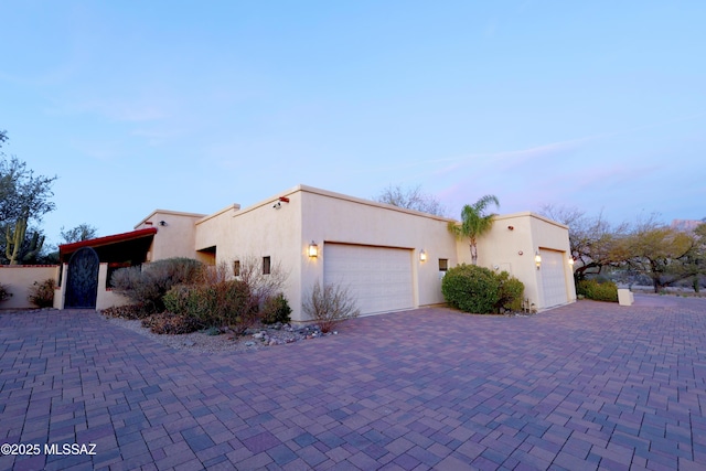 exterior space featuring a garage, decorative driveway, and stucco siding