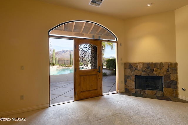 entryway featuring carpet, visible vents, a fireplace, and baseboards