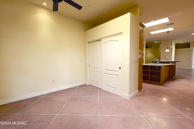 unfurnished bedroom with light tile patterned floors, a sink, visible vents, baseboards, and a closet