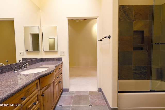 full bathroom featuring baseboards, combined bath / shower with glass door, and vanity