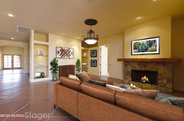 tiled living room featuring a stone fireplace, recessed lighting, visible vents, baseboards, and built in features