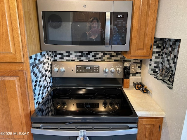 kitchen featuring appliances with stainless steel finishes, light countertops, brown cabinetry, and backsplash