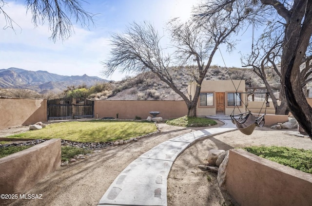 exterior space featuring a mountain view, a lawn, fence, and a gate