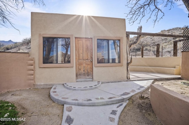 doorway to property featuring fence and stucco siding