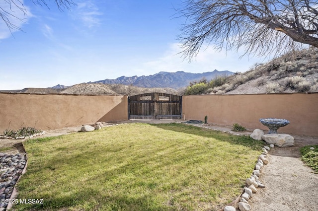 view of yard with a mountain view, fence, and a gate