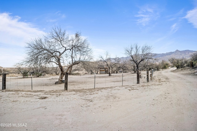 view of yard featuring fence, a mountain view, and a rural view