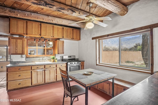 kitchen with beam ceiling, wood ceiling, a sink, ceiling fan, and stainless steel gas range