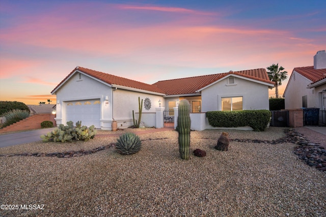 mediterranean / spanish house featuring a garage, a fenced front yard, a gate, and stucco siding