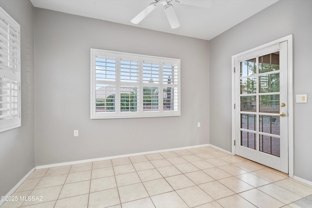 spare room featuring light tile patterned floors, a ceiling fan, and baseboards