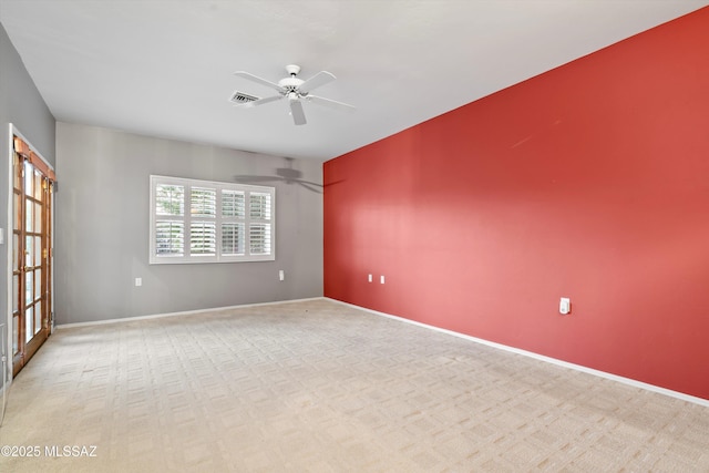 spare room with baseboards, visible vents, a ceiling fan, and light colored carpet