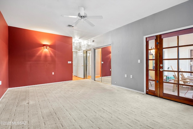 carpeted empty room with a ceiling fan, visible vents, and baseboards