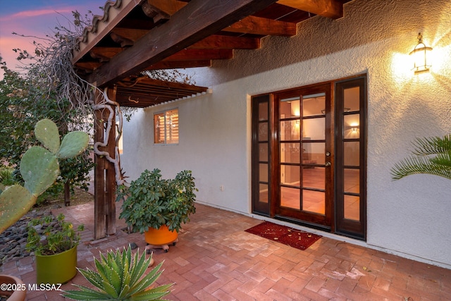 exterior entry at dusk with a patio area and stucco siding