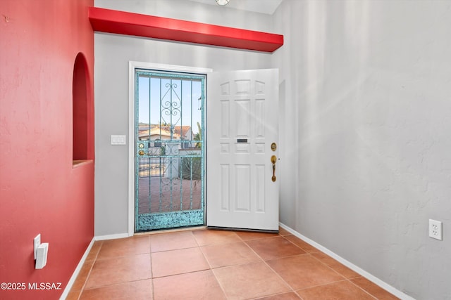 tiled foyer entrance with a textured wall and baseboards