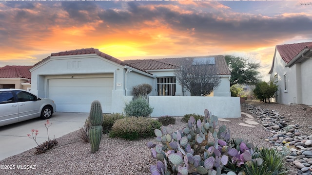 view of front facade featuring an attached garage, stucco siding, concrete driveway, and a tiled roof