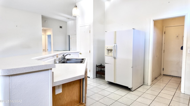 kitchen featuring a peninsula, white refrigerator with ice dispenser, a sink, and light tile patterned flooring