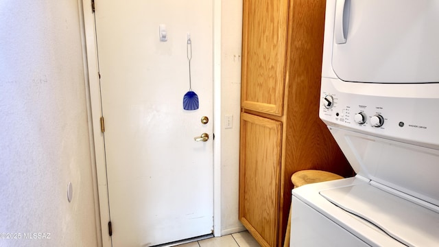 laundry room featuring stacked washer and clothes dryer, light tile patterned flooring, and laundry area