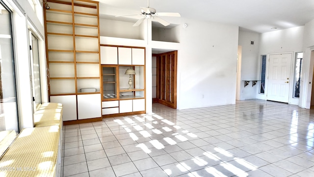 unfurnished living room featuring light tile patterned floors, ceiling fan, and a high ceiling