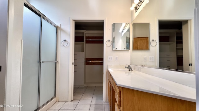 bathroom with a shower with door, vanity, a walk in closet, and tile patterned floors