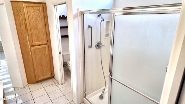 bathroom with tile patterned flooring, a closet, a shower stall, and toilet