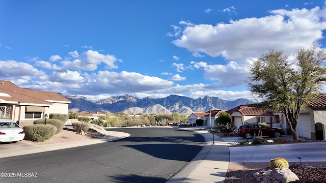 view of road featuring curbs, a residential view, a mountain view, and sidewalks