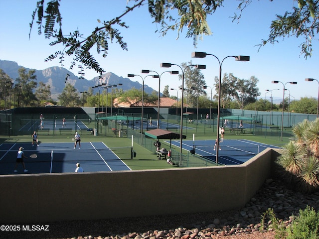 view of tennis court featuring fence and a mountain view