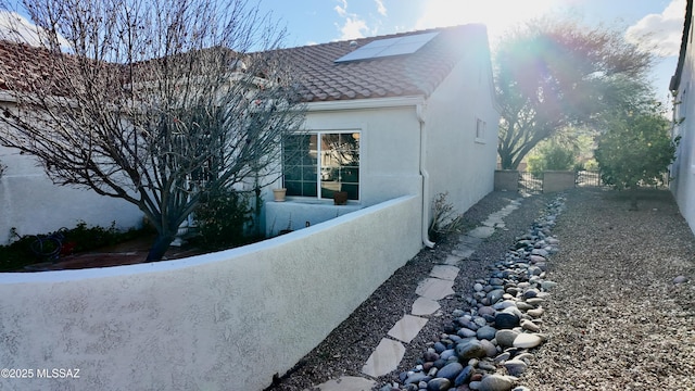 view of home's exterior with solar panels, fence, and stucco siding