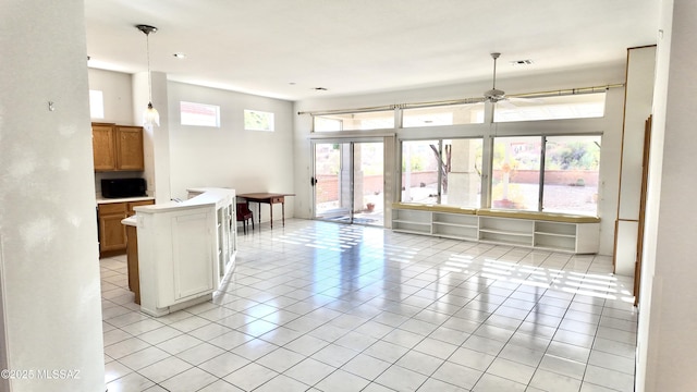 kitchen featuring light tile patterned flooring, a ceiling fan, light countertops, brown cabinetry, and decorative light fixtures