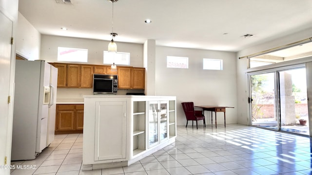 kitchen with white refrigerator with ice dispenser, decorative light fixtures, brown cabinets, visible vents, and a towering ceiling