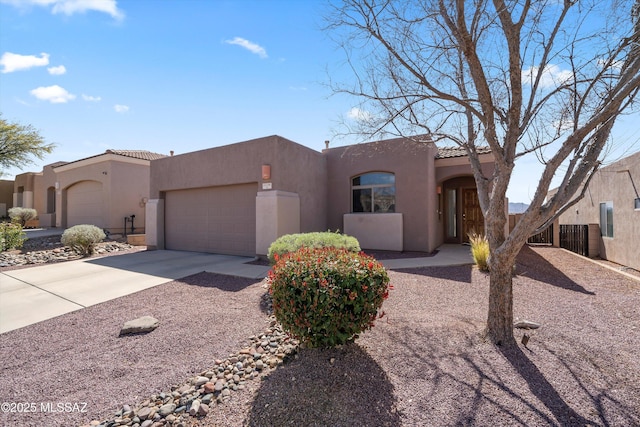 southwest-style home featuring a tile roof, concrete driveway, a garage, and stucco siding